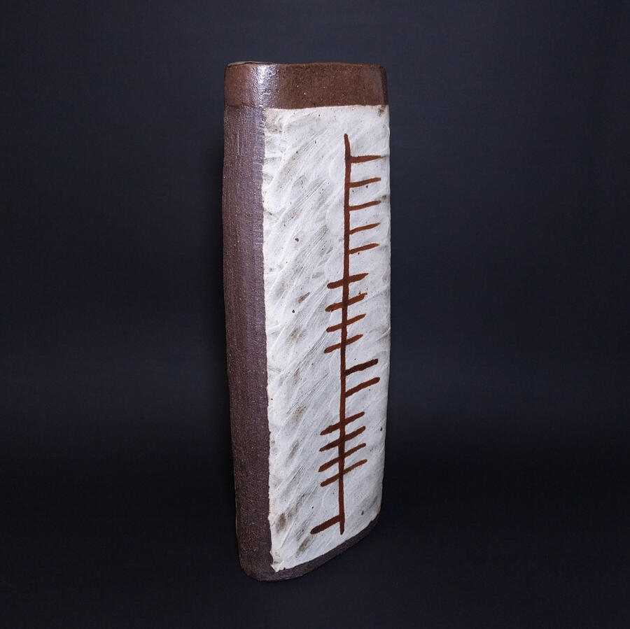 Tall, slender vase in black clay with Helen written in primitive Irish Ogham alphabet, tree letters
